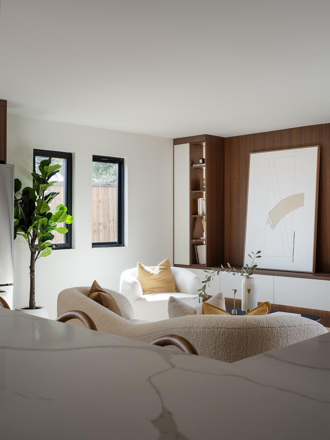 A cream sofa and sculptural armchair framed by a dark wood accent wall